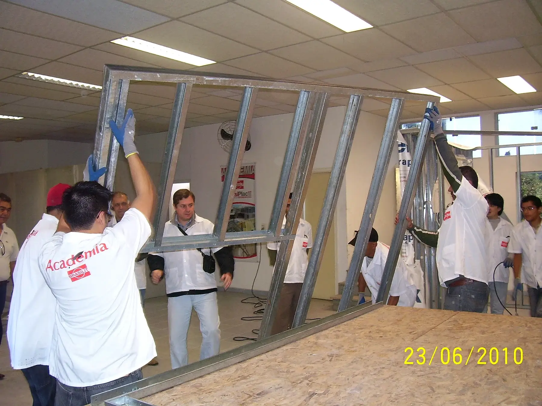 Participantes movimentando um painel de perfis de aço durante treinamento da Academia Brasilit em 2010.